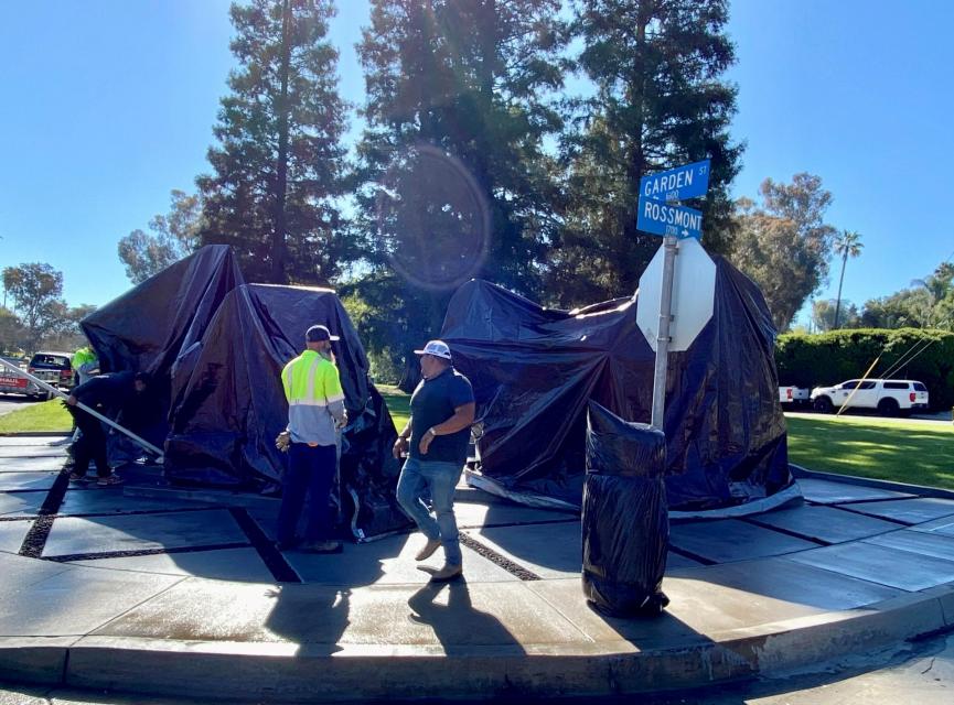 City workers cover sculpture, Peloton Takes the Classic Curve, after installation.